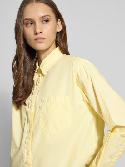 Vrouwenmodel draagt Boyfriend Fit Bluse met borstzak Model 'HARLIE' van Levi's®, zuiver katoen in lichtgeel, overhemdkraag, labeldetail, zijaanzicht borst, close-up.
