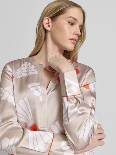 Vrouwenmodel draagt Bluse mit Tunika-Kragen und abgerundetem Saum van HERZENS in beige met wit-rood motief, rechte fit, tuniekkraag, afgeronde zoom, ruglengte maat 36: 68 cm, mouwlengte 36: 64 cm, close-up bovenlichaam.