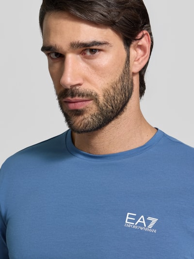 Männermodel trägt Regular Fit T-Shirt mit Logo-Print von EA7 Emporio Armani, elastischer Baumwoll-Mix, Rundhalsausschnitt, Nahaufnahme Oberkörper.