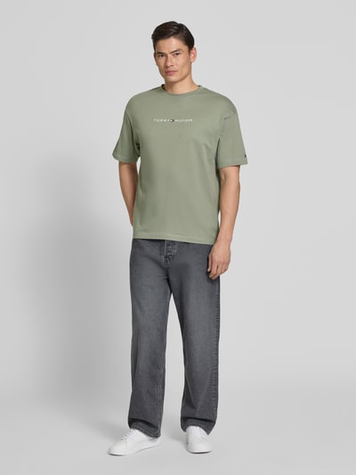 Männermodel trägt Regular Fit T-Shirt mit Label-Schriftzug aus reiner Baumwolle von Tommy Hilfiger, Optik: Unifarben, Ganzkörperansicht von vorne.