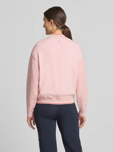 Frauenmodel trägt Regular Fit Strickjacke aus Viskose-Mix von Marc Cain in Rosa mit Kontraststreifen, Strukturmuster, Ganzkörperansicht Rückansicht, Rückenlänge 59 cm, Ärmellänge 58 cm, Stehkragen, Zweiwege-Reißverschluss, Baumwoll-Anteil.