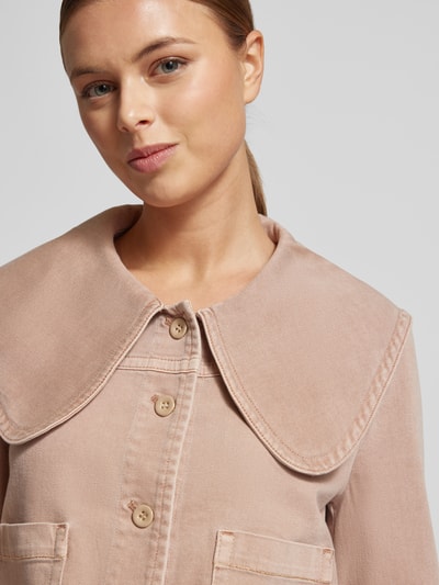 Frauenmodel trägt Regular Fit Jeansjacke mit Umlegekragen von Marc Cain in Beige, aufgesetzte Taschen, Knopfleiste, Nahaufnahme Oberkörper.