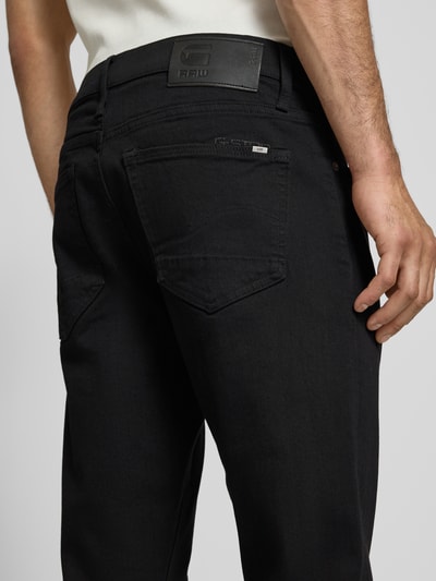 Männermodel trägt Slim Fit Jeans im 5-pocketmodel von G-Star Raw aus katoenmix met stretch, donker met zwarte stiksels, detailaufnahme Rückansicht. Context: heren slim fit jeans van G-Star Raw, katoenmix met stretch, slim fit, 5-pocketmodel, knoop- en ritssluiting, bandwijdte maat 32/32: 46 cm, binnenbeenlengte maat 32/32: 80 cm.