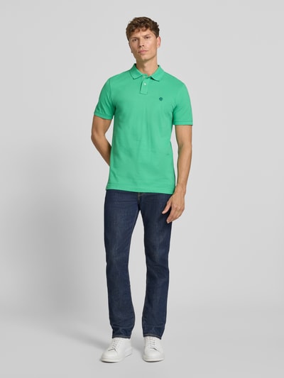Männermodel trägt Slim Fit Poloshirt mit Label-Stitching von MCNEAL aus Reine Baumwolle, Knopfleiste, Rückenlänge 72 cm bei Größe M, Ganzkörperansicht von vorne.