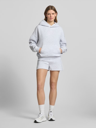 Frauenmodel trägt Regular Fit Sweatshorts mit Spitzenbesatz von Review, Material-Mix mit Baumwoll-Anteil, hellgrau, elastischer Bund, Ganzkörperansicht von vorne.