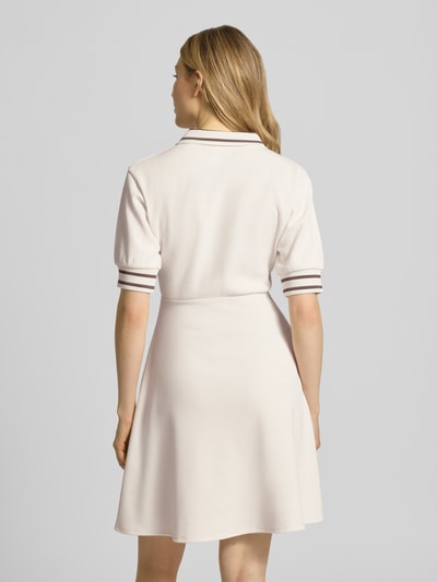 Vrouwenmodel draagt Minikleid mit Polokragen und Logo-Stitching van ARMANI EXCHANGE in licht beige, materiaalmix met viscose, getailleerd model, polokraag, korte ritssluiting, gestikt logo, ruglengte maat S 92 cm, borstwijdte 47 cm, mouwlengte 28 cm, stof met gladde textuur. Volledige lichaamsaanzicht achteraan.
