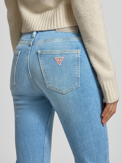 Kobiece model nosi Flared Jeans mit 5-Pocket-Design von Guess, mieszanka bawełny z dodatkiem streczu, rozkloszowany krój, jasnoniebieskie, detal z tyłu, zapięcie na guzik i zamek błyskawiczny, szerokość w rozmiarze 27/32: 38 cm, długość wewnętrzna nogawki: 80 cm, zbliżenie na biodra