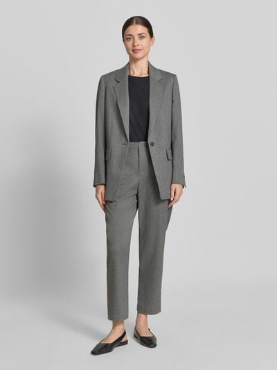 Modelka kobieca ma na sobie szare spodnie materiałowe z modelu 'Stoffhose mit Gesäßtaschen Modell DISPATCH' od Drykorn z mieszanki materiałów z wiskozą, krój regular fit, zaprasowane fałdy, kieszenie z tyłu, szerokość w rozmiarze 27/34: 40 cm, długość wewnętrzna nogawki w rozmiarze 27/34: 67 cm, widok całej sylwetki z przodu.