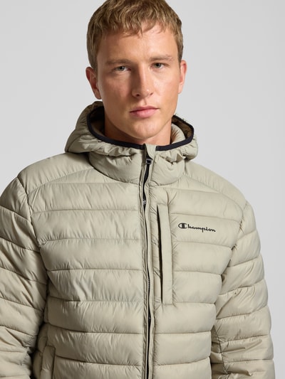 Männermodel draagt Steppjacke met capuchon en logoprint van CHAMPION, regular fit, ritssluiting, steekzakken, nahaufnahme bovenlijf.