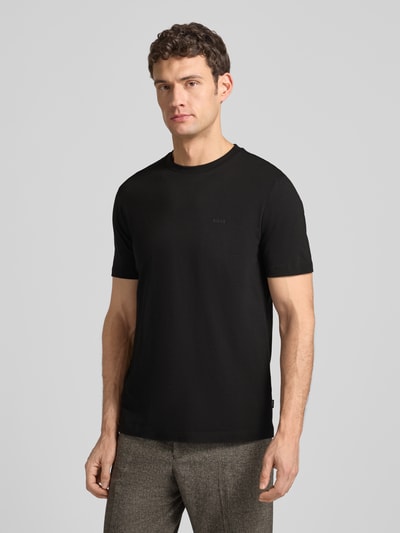 Männermodel trägt Herren T-Shirt aus reiner Baumwolle Modell 'Thompson' von BOSS mit geradem Schnitt, dezentem Logo-Print, Ganzkörperansicht von vorne.