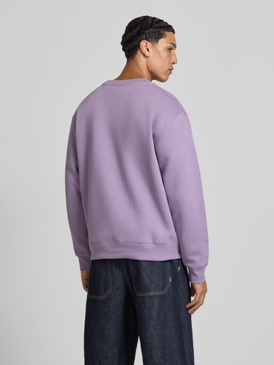 Männermodel trägt Sweatshirt mit Rundhalsausschnitt und Label-Stitching von New Balance in Flieder, Baumwoll-Mix, Relaxed-Fit, Rückenlänge 67 cm, Ärmellänge 63 cm, Ganzkörperansicht Rückansicht.