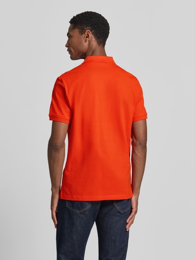 Männermodel trägt Regular Fit Poloshirt aus reiner Baumwolle von Tom Tailor in kräftigem Orange, Ganzkörperansicht Rückansicht.