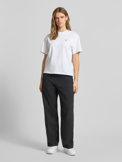 Frauenmodel trägt Relaxed Fit Jeans mit Eingrifftaschen Modell 'Brandon' von Carhartt Work In Progress aus Reine Baumwolle in dunklem Grau, kombiniert mit weißem Damen T-Shirt, Jeans-Look, Bundweite 40 cm, Innenbeinlänge 72 cm, Ganzkörperansicht von vorne.