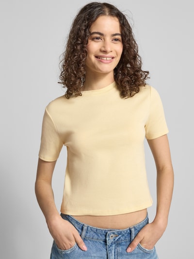 Modelka prezentuje damski t-shirt z bawełny o taliowanym kroju, z okrągłym dekoltem, krój krótki, długość tyłu w rozmiarze S: 47 cm, T-Shirt mit Rundhalsausschnitt od Topshop, jasny kolor, gładka faktura, całkowity widok z przodu.