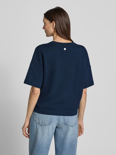 Frauenmodel trägt Boxy Fit T-Shirt Modell 'Tilina' von JOOP! aus Baumwoll-Mix in Dunkelblau, lockere Form, Ganzkörperansicht Rückansicht.