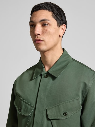 Männermodel trägt Regular Fit Hemdjacke aus Baumwolle von Kenzo in Dunkelgrün mit Brusttaschen und Umlegekragen, Nahaufnahme Oberkörper.