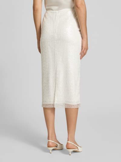 Frauenmodel trägt Bleistiftrock mit rückseitigem Gehschlitz von Marc Cain in Creme mit Pailletten, körpernah geschnitten, Ganzkörperansicht Rückansicht.