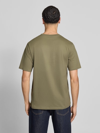 Męski model nosi T-Shirt mit Logo und Rundhalsausschnitt von Jack & Jones z bawełny ekologicznej, krój regular fit, okrągły dekolt, logo, długość tyłu w rozmiarze M: 68 cm, jednolity kolor, gładka tekstura, widok całej sylwetki z tyłu.