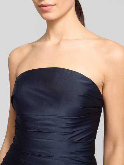 Modelka nosi Regular Fit Abendkleid in Falten-Optik od Luxuar, satyna, krój regular fit, fason taliowany, dekolt odsłaniający ramiona, linia A, fałdy, zamek kryty, głęboki granat, tekstura gładka, szerokość w rozmiarze 36: 41 cm, długość pleców: 125 cm, zbliżenie górnej części ciała