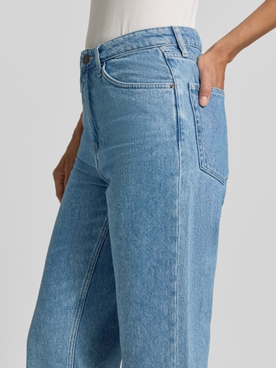 Kobiece modelka ma na sobie Straight Fit Jeans aus reiner Baumwolle Modell 'Joybird' von American Vintage w jasnoniebieskim kolorze, faktura klasycznego denimu, 5 kieszeni, zapięcie na guzik i zamek błyskawiczny, krój straight fit, skrócona długość, szerokość w rozmiarze 27/32: 38 cm, długość wewnętrzna nogawki w rozmiarze 27/32: 65 cm, bawełna; zbliżenie na biodra i kieszenie, widok z przodu.