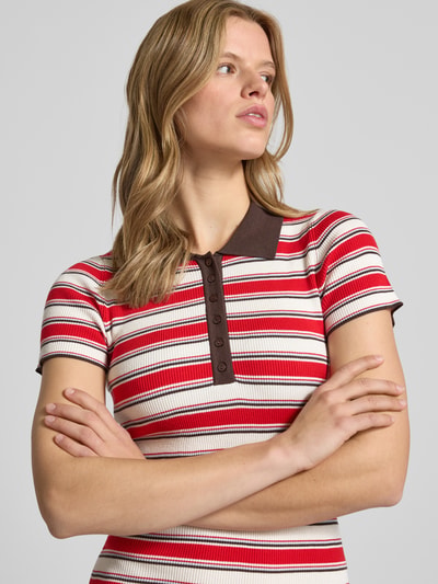 Frauenmodel trägt Polokleid aus Viskose-Mix mit kurzer Knopfleiste Modell 'Elenia' von LeGer by Lena Gercke, gestreift in Rot, Braun und Creme, körpernaher Schnitt, Nahaufnahme Oberkörper.