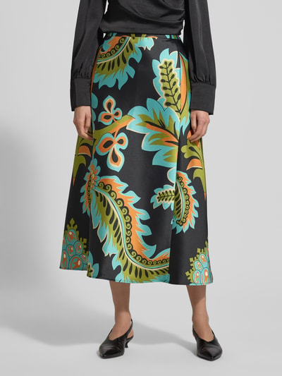 Frauenmodel trägt Midirock aus Satin im Allover-Look von HERZENS, bunte Paisleymuster, A-Linie, Teilungsnähte, Reißverschluss, Ganzkörperansicht von vorne. Bundweite bei Größe 36: 39 cm, Gesamtlänge bei Größe 36: 90 cm.