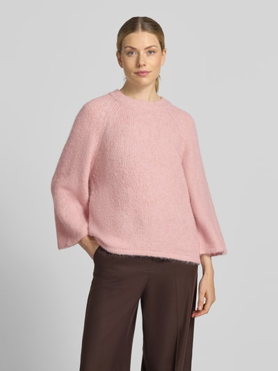 Kobiece model prezentuje sweter z dzianiny 'Strickpullover mit Raglanärmeln' od FREE/QUENT, mieszanka materiałów z dodatkiem wełny, prosty krój, okrągły dekolt, raglanowe rękawy, długość tyłu 54 cm, długość rękawów 50 cm, jasnoróżowy, tekstura puszysta, szeroki fason, widok całej sylwetki z przodu.
