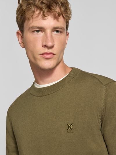 Männermodel trägt Regular Fit Pullover aus reiner Baumwolle Modell 'San Celio-C' von HUGO in Olivgrün mit glatter Textur, Nahaufnahme Oberkörper, Herren Pullover von HUGO Blue.