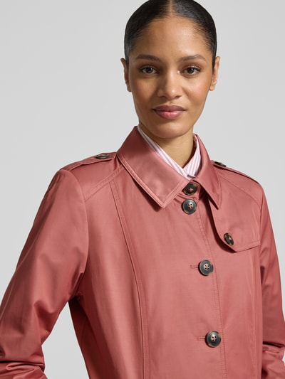 Frauenmodel trägt Trenchcoat mit Ärmelriegeln von Fuchs Schmitt in Rosa mit Umlegekragen, Knopfleiste, Nahaufnahme Oberkörper