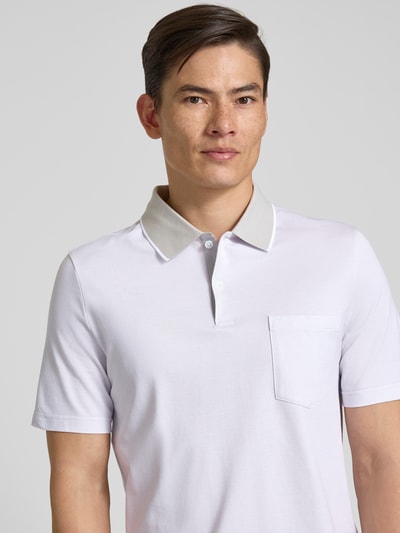 Męski model nosi Regular Fit Poloshirt mit Strukturmuster und Brusttasche von MAERZ Muenchen, bawełna, kołnierzyk polo, biała faktura, krótka listwa guzikowa, kieszeń na piersi, detal z logo, długość tyłu w rozmiarze 50: 71 cm, zbliżenie na górną część ciała z przodu.