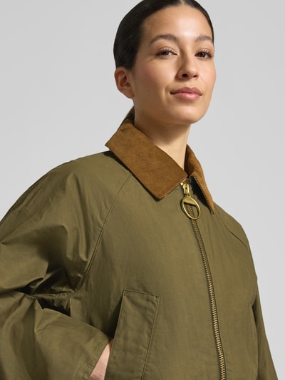 Vrouwenmodel draagt Regular fit functioneel jack uit puur katoen model 'LANESHAW' van Barbour, look: effen, platte kraag, ritssluiting, applicatie met labelstitching, lange mouw, waterdicht, klepzakken, puur katoen, detailopname bovenlichaam.