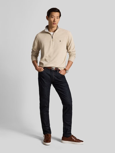Männermodel trägt Regular Fit Sweatshirt aus Baumwoll-Mix von Polo Ralph Lauren in Beige mit dunkler Hose, Ganzkörperansicht von vorne.