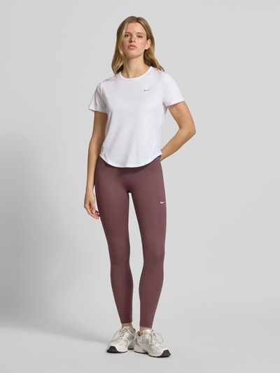Frauenmodel trägt Leggings mit Logo von NIKE TRAINING in Lila mit körpernaher Passform, elastischem Bund und Stretch-Anteil, Ganzkörperansicht von vorne.