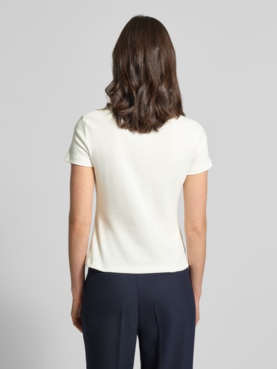 Modelka nosi Slim Fit T-Shirt aus reiner Baumwolle von Tommy Hilfiger, efekt: jednolity kolor, detal z logo, ozdobne guziki, dekolt w łódkę, krótki rękaw, wykończenie materiału: czysta bawełna, widok całej sylwetki od tyłu.