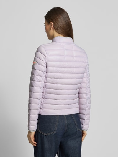 Modelka nosi Steppjacke mit Reißverschlusstaschen Modell 'SISTER JUDY' von Frieda & Freddies, jasnofioletowa, krój slim fit, stójka, długość tyłu w rozmiarze 36: 56 cm, szerokość ramion w rozmiarze 36: 41 cm, szerokość klatki piersiowej w rozmiarze 36: 47 cm, długość rękawa w rozmiarze 36: 61 cm, widok całej sylwetki z tyłu.
