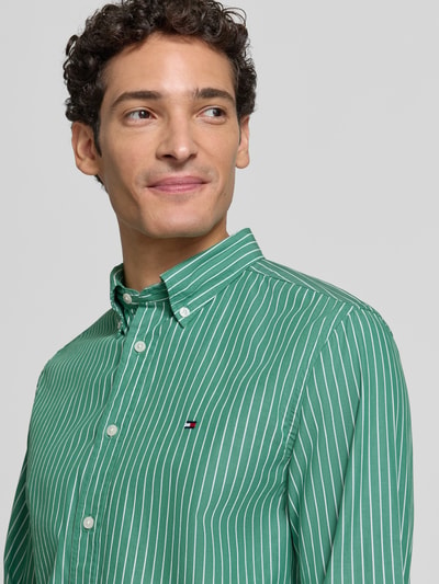 Männermodel trägt Body Fit Freizeithemd aus reiner Baumwolle von Tommy Hilfiger in grün mit weißen Streifen, Nahaufnahme Oberkörper. Herren Freizeithemd von Tommy Hilfiger.