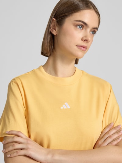 Modelka nosi Regular Fit T-Shirt mit Logo-Print od adidas Sportswear, bawełna, krój regular fit, krótki rękaw, zbliżenie górnej części ciała.