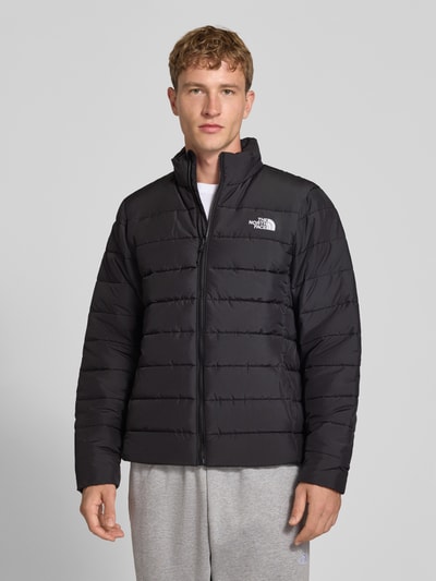 Männermodel trägt schwarze Regular Fit Jacke in Stepp-Optik Modell 'ACONCAGUA' von The North Face mit Stehkragen, Ganzkörperansicht von vorne.