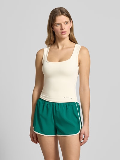 Frauenmodel trägt Slim Fit Top mit Logo-Detail Modell 'Refine' von P.E Nation aus elastischem Material-Mix in Creme, Ganzkörperansicht von vorne. Rückenlänge bei Größe S: 45 cm.