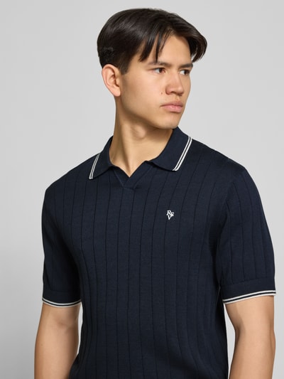 Männermodel trägt Slim Fit Polo-Strickshirt mit Logo-Stickerei von REVIEW, Reine Baumwolle, Ripp-Optik, Nahaufnahme Oberkörper.