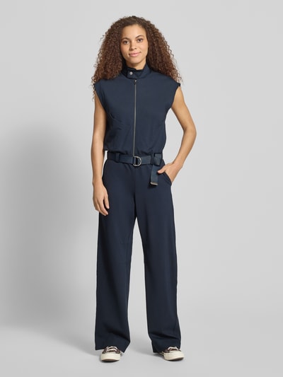 Vrouwenmodel draagt Jumpsuit aus Viskose-Mix mit Reißverschluss und Gürtel van G-Star Raw in donkerblauw, regular fit, met stretch, opstaande kraag, ritssluiting en riem, borstwijdte 46 cm, ruglengte 51 cm, totale lengte 160 cm, binnenbeenlengte 85 cm. Ganzkörperansicht van voren.
