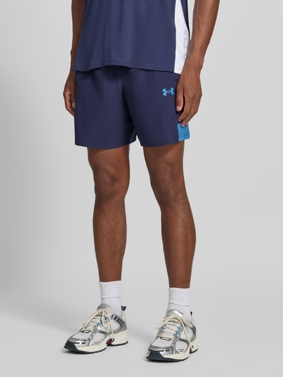 Männermodel trägt Regular Fit Sportshorts mit elastischem Bund model 'UTILITY' van Under Armour in donkerblauw met lichtblauwe details, heren sportshorts, nahaufnahme onderlichaam.