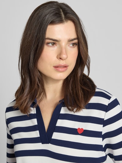 Frauenmodel trägt Regular Fit Poloshirt mit Viskose-Anteil Modell 'Februar' von More & More, weiß-blau gestreift, Kurzarmpolokragen, Nahaufnahme Oberkörper.
