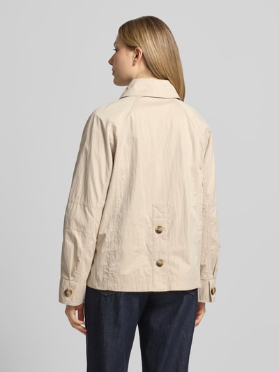 Vrouwenmodel draagt Jacke mit seitlichen Eingrifftaschen und Kentkragen van Fuchs Schmitt in beige, recht model, ruglengte maat 36: 64 cm, schouderbreedte: 38 cm, borstwijdte: 51 cm, mouwlengte: 44 cm, knoopsluiting, raglanmouwen, steekzakken, ganzekörperaanzicht achterkant