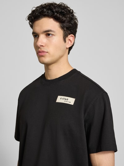 Männermodel trägt Relaxed Fit T-Shirt mit Label-Badge von G-Star Raw aus reiner Baumwolle, Rundhalsausschnitt, Nahaufnahme Oberkörper.