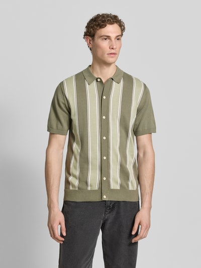 Męski model nosi Polo-Cardigan mit 1/2-Arm od Lindbergh, bawełna, krój regular fit, guzik, oliwkowo-białe paski, zdjęcie całej sylwetki z przodu.
