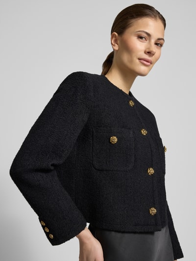 Frauenmodel trägt Regular Fit Blazer mit Rundhalsausschnitt Modell 'MEREDITH' von Bash aus reiner Baumwolle, strukturierte Oberfläche, schwarze Farbe, goldene Knöpfe, Brusttaschen, Nahaufnahme Oberkörper.