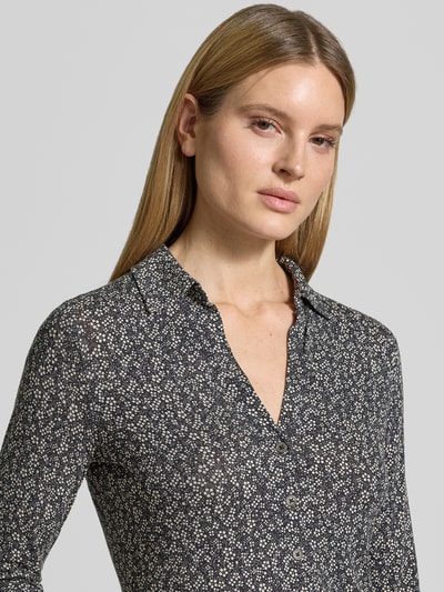 Modelka nosi Shaped Fit Blusenshirt aus Viskose-Mix von Marc O'Polo, efekt: kwiatowy wzór na całej powierzchni, krój shaped fit, kołnierzyk koszulowy, dekolt w serek, listwa guzikowa, rękaw o dł. 3/4, wykończenie materiału: mieszanka wiskozy, pas na plecach, zbliżenie na górną część ciała.