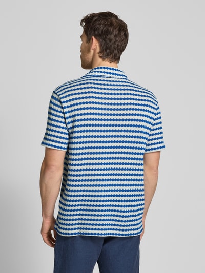 Männermodel trägt Relaxed Fit Poloshirt aus Baumwoll-Mix Modell 'DYLAN' von SELECTED HOMME, efekt: wzór na całej powierzchni, kołnierz z połami, dekolt w serek, listwa guzikowa, krótki rękaw, drobny splot, mieszanka bawełny, widoczne odcienie bieli i niebieskiego, Ganzkörperansicht Rückansicht.