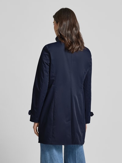 Frauenmodel trägt dunkelblauen Trenchcoat mit Stehkragen und Ärmelriegeln von Christian Berg Woman Selection, Ganzkörperansicht Rückansicht. A-Linienform, glatte Textur, Knopfleiste, Rückenlänge 84 cm, Schulterbreite 39 cm, Brustweite 47 cm, Ärmellänge 63 cm.